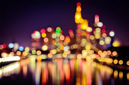 A vibrant bokeh depiction of a city skyline at night, with colorful lights reflecting on the water, creating an artistic and dreamlike atmosphere for a HD desktop wallpaper.
