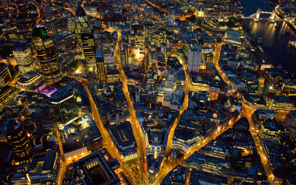 A stunning HD wallpaper of London's vibrant skyline at night, showcasing intricate city streets illuminated by city lights. A captivating man-made landscape.