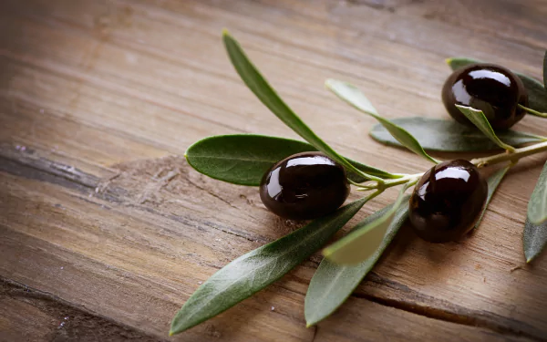 A close-up of dark olives on a wooden surface, showcasing their natural beauty. This HD desktop wallpaper adds a touch of elegance and culinary inspiration.