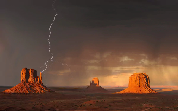 A striking lightning bolt illuminates Monument Valley's iconic sandstone formations against a dramatic desert sky, creating a captivating HD wallpaper backdrop.
