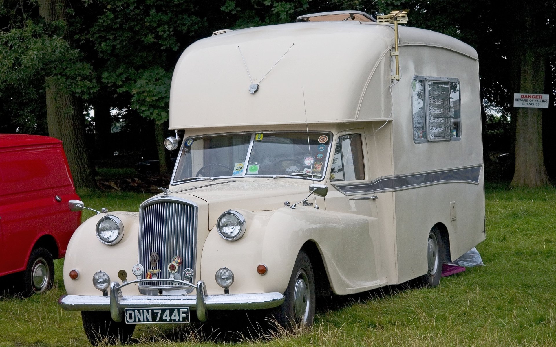 HD desktop wallpaper featuring a vintage cream-colored motorhome parked on grass near trees, blending classic vehicle charm with nature.