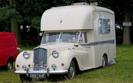 HD desktop wallpaper featuring a vintage cream-colored motorhome parked on grass near trees, blending classic vehicle charm with nature.