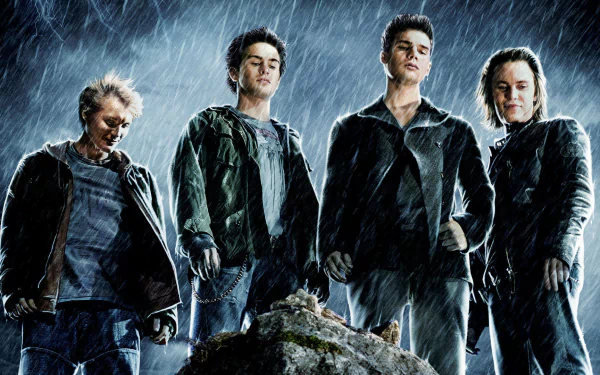 Four young men in dark jackets stand on rocky ground in pouring rain, brooding and powerful — HD PC desktop wallpaper from the movie The Covenant (2006).