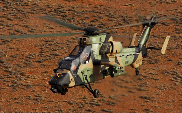 HD desktop wallpaper featuring a Eurocopter Tiger attack helicopter in flight over a rugged, reddish terrain.