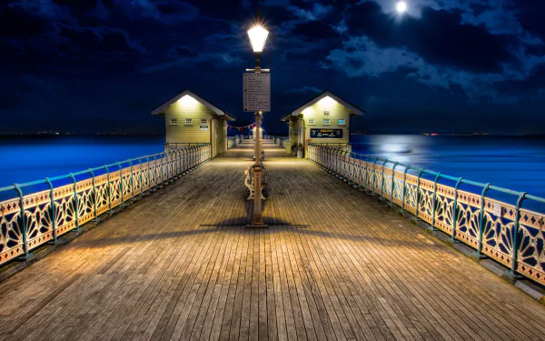 Man-made pier illuminated at night under a cloudy sky, captured in high definition as a PC desktop wallpaper and background.