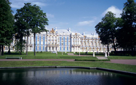 HD desktop wallpaper featuring the man-made Catherine Palace framed by trees, with a reflecting pool in the foreground under a clear blue sky.