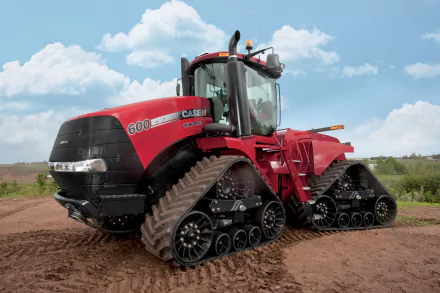4K Ultra HD image of a red Case Quadtrac tractor with four track wheels on a dirt field under a partly cloudy sky.