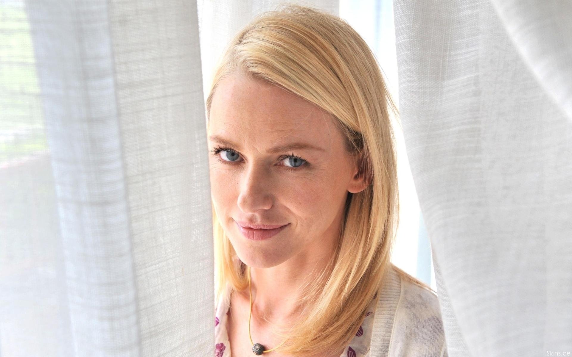 HD PC desktop wallpaper featuring a close-up portrait of celebrity Naomi Watts with soft natural lighting and light-colored curtains in the background.