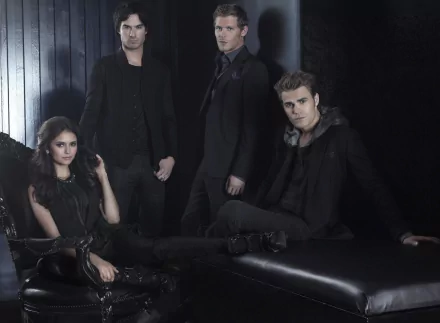 A dramatic promotional image from the TV show The Vampire Diaries, featuring the main characters in dark attire, posed against a sleek backdrop.