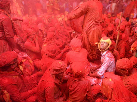 A vibrant HD desktop wallpaper showing a crowd covered in red dirt, capturing dynamic photography of people immersed in a colorful, intense scene.