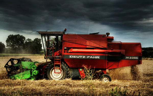 HD PC desktop wallpaper of a red Duetz-Fahr harvester vehicle in a harvested field under dramatic stormy skies, agricultural background.