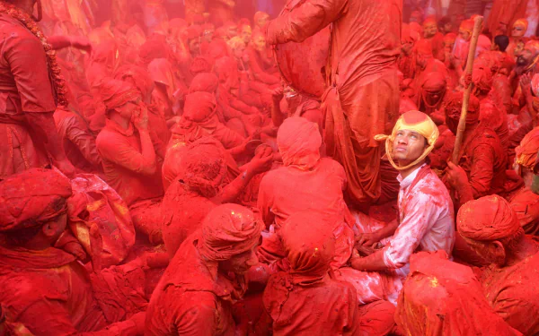 A vibrant HD desktop wallpaper showing a crowd covered in red dirt, capturing dynamic photography of people immersed in a colorful, intense scene.