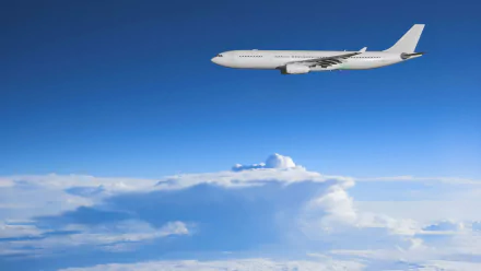 HD desktop wallpaper featuring a white aircraft flying above fluffy clouds against a clear blue sky.