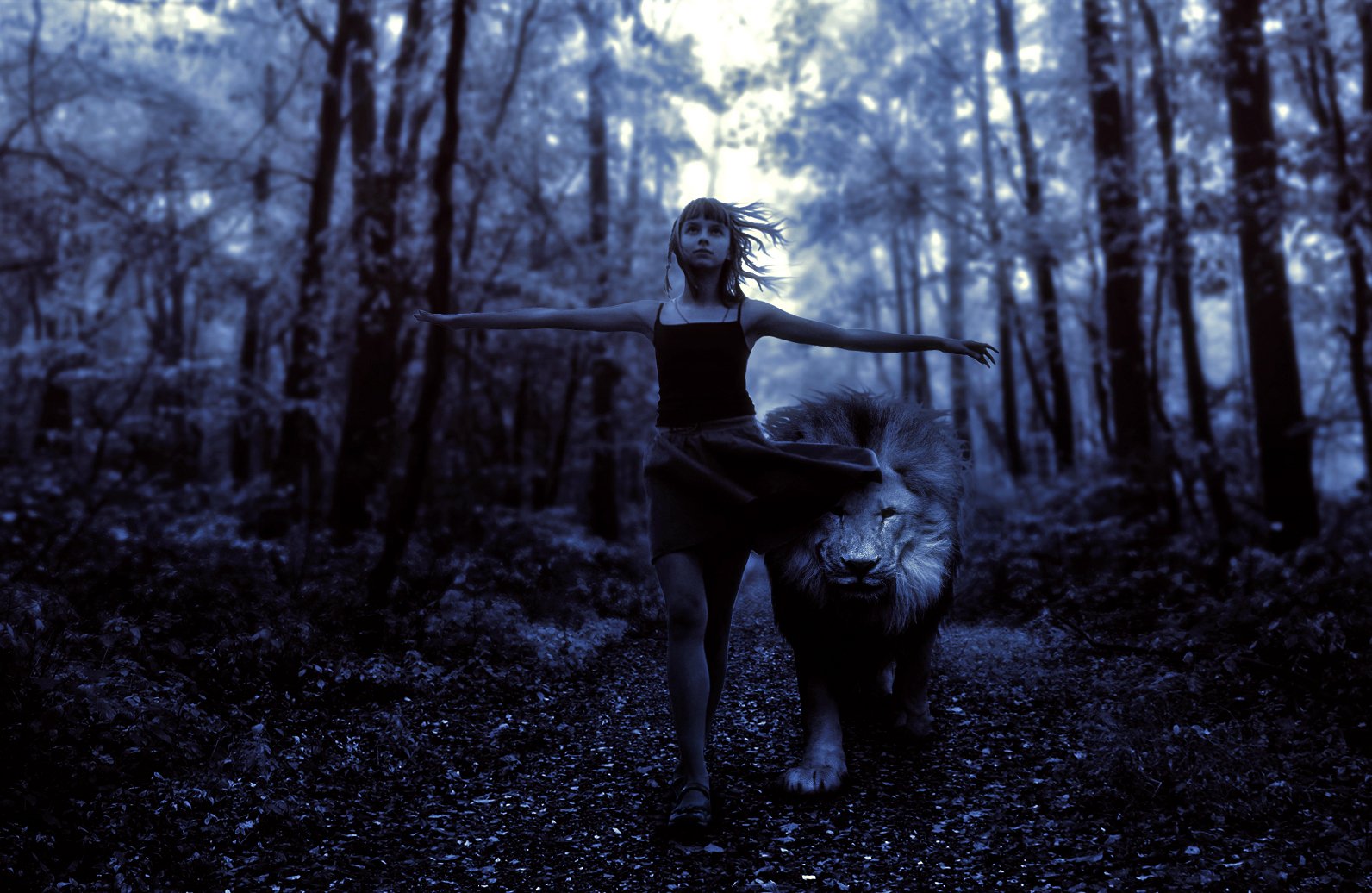 A child dances in a serene forest alongside a majestic lion, captured in a striking blue-tinted photograph, creating a magical and enchanting scene for a desktop wallpaper.