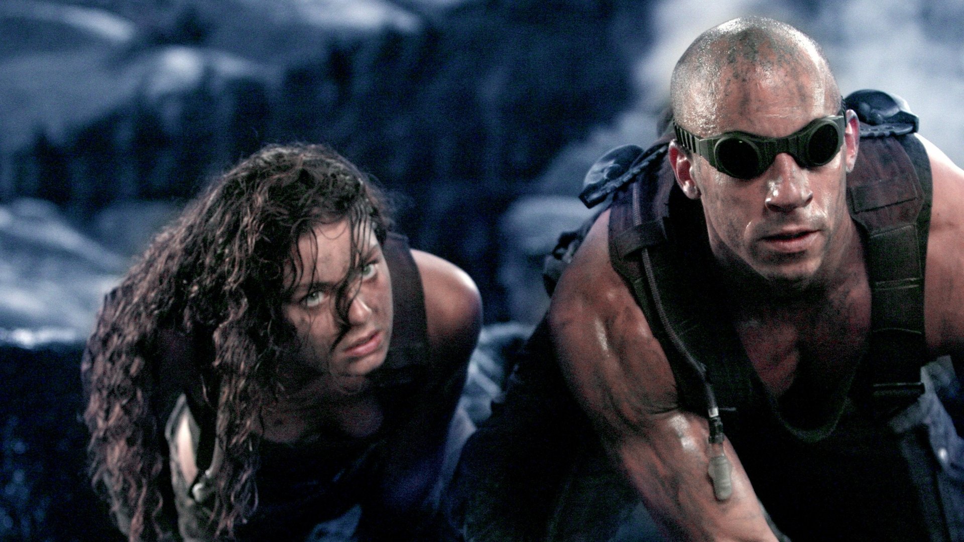 2K Quad HD PC desktop wallpaper: gritty scene from the movie The Chronicles of Riddick with two battle-worn characters crawling across rocky terrain.