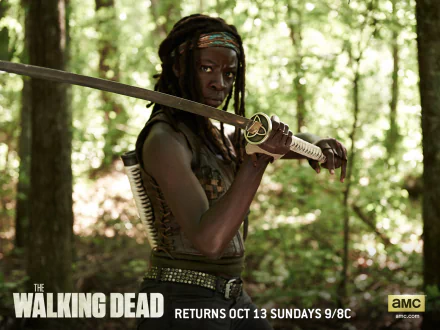Danai Gurira as Michonne from The Walking Dead wields a katana in this striking HD wallpaper, set in a lush forest backdrop. A true homage to the iconic character.
