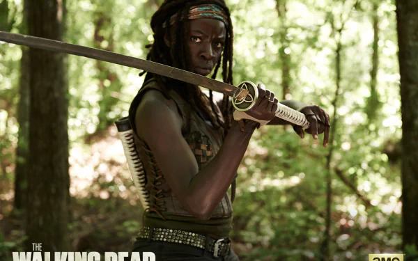 Danai Gurira as Michonne from The Walking Dead wields a katana in this striking HD wallpaper, set in a lush forest backdrop. A true homage to the iconic character.