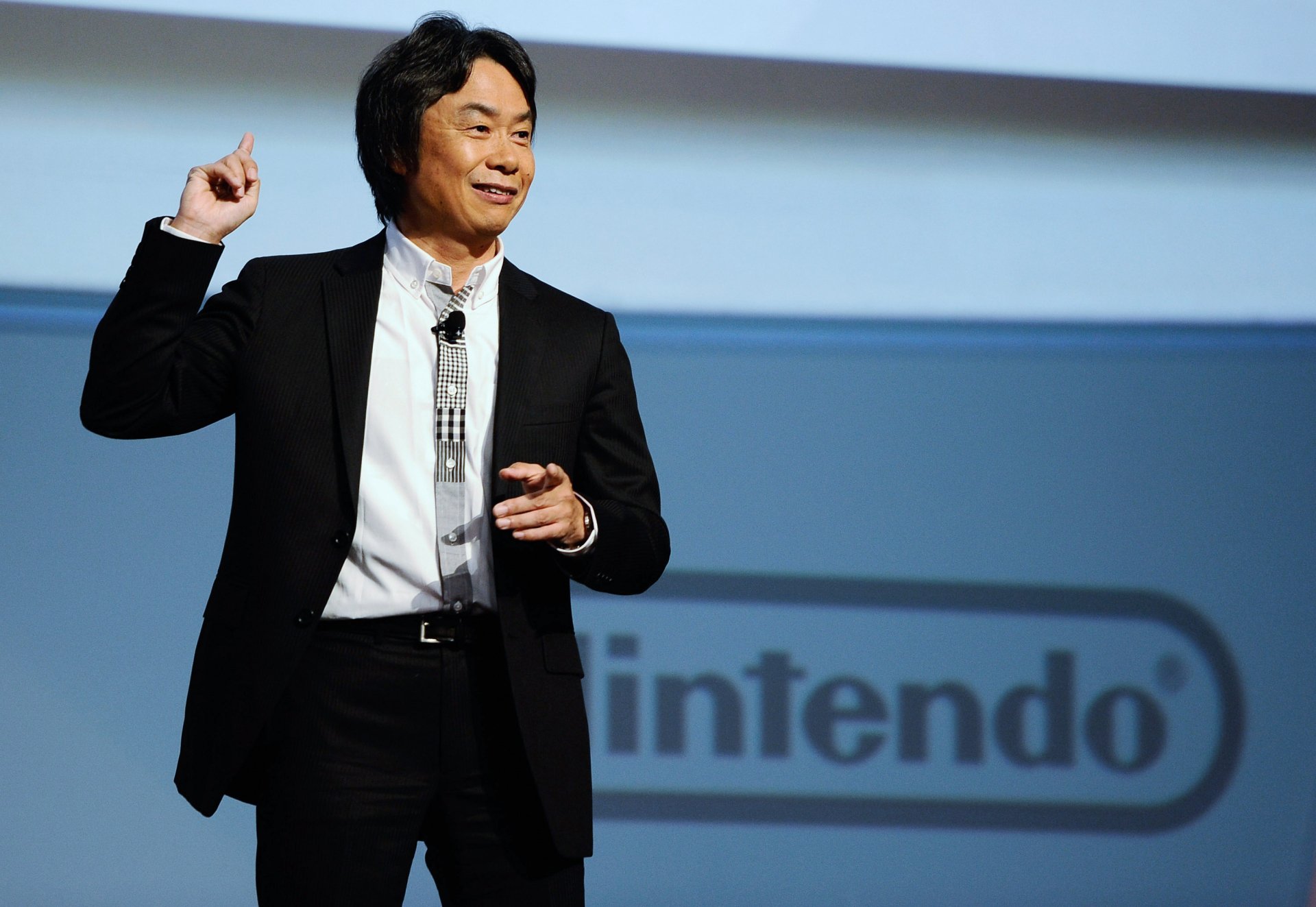 HD desktop wallpaper featuring Shigeru Miyamoto speaking at a Nintendo event.