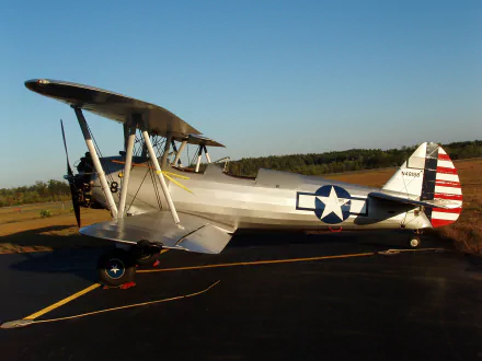 HD PC desktop wallpaper featuring a vintage military biplane with U.S. Air Force insignia parked on a runway under a clear blue sky.