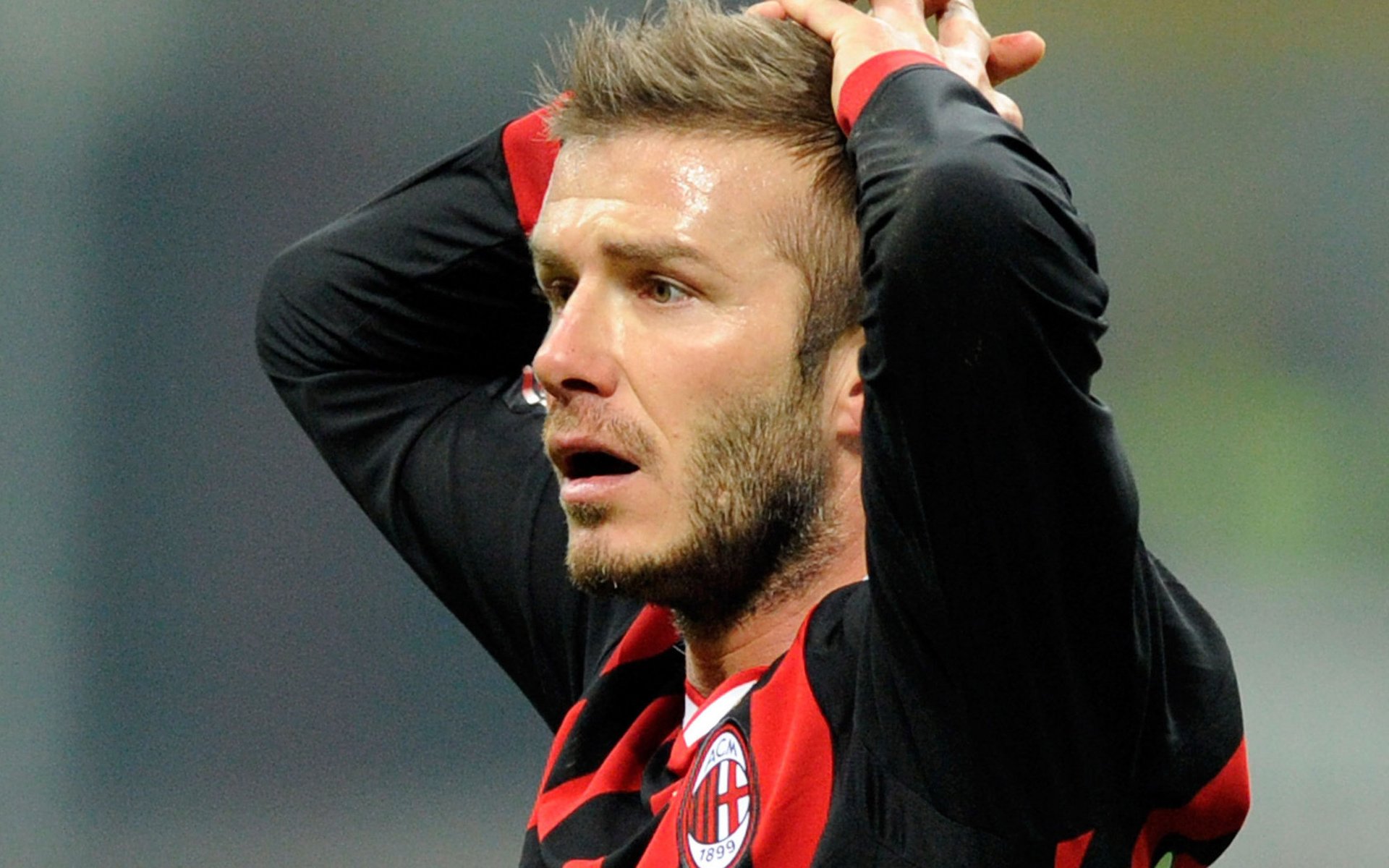 HD PC desktop wallpaper of a male professional footballer (sports), close-up in a red-and-black kit with hands on his head during a match.