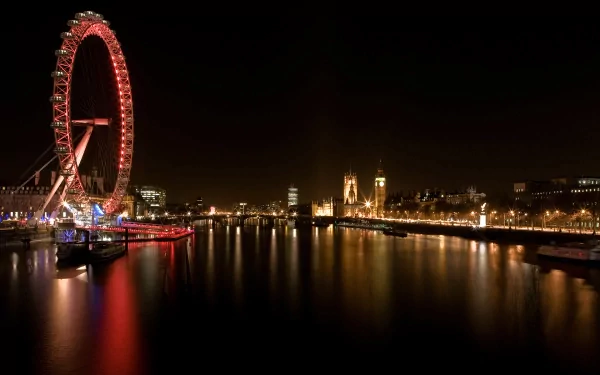 Night view of the illuminated London Eye and cityscape reflecting on the River Thames, captured in a high-definition desktop wallpaper from London.