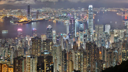 A stunning HD wallpaper showcasing the vibrant cityscape of Hong Kong at night, featuring a skyline filled with illuminated skyscrapers and a sparkling harbor.