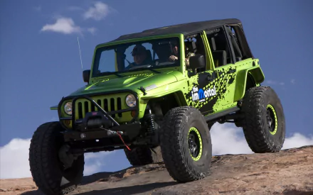 A green Jeep climbs a rocky terrain under a clear blue sky, showcasing its rugged design. This HD wallpaper captures the spirit of adventure and off-road exploration.