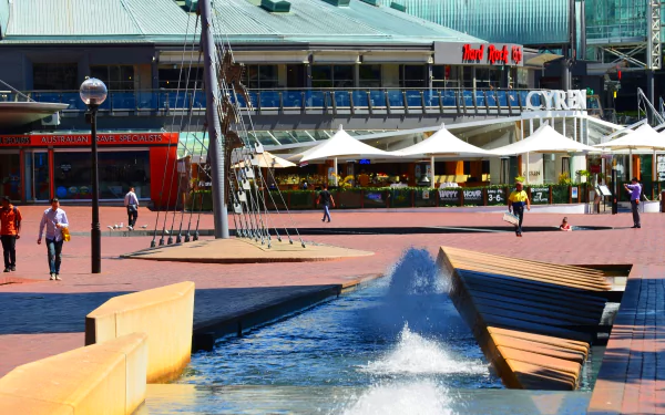 Darling Harbour, Sydney — man-made plaza with shops and buildings, people strolling beside a stepped fountain; 2K Quad HD PC desktop wallpaper.
