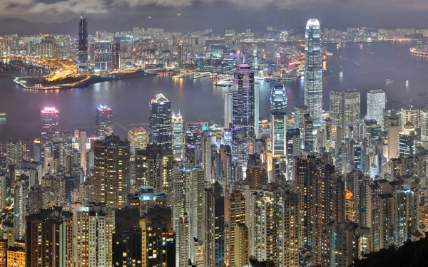 A stunning HD wallpaper showcasing the vibrant cityscape of Hong Kong at night, featuring a skyline filled with illuminated skyscrapers and a sparkling harbor.
