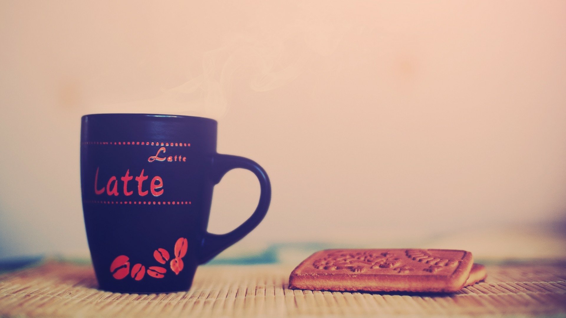 A cozy latte in a dark mug steams beside a beautifully designed cookie, set against a soft background, capturing the essence of coffee and comfort. Perfect HD wallpaper for a food lover.