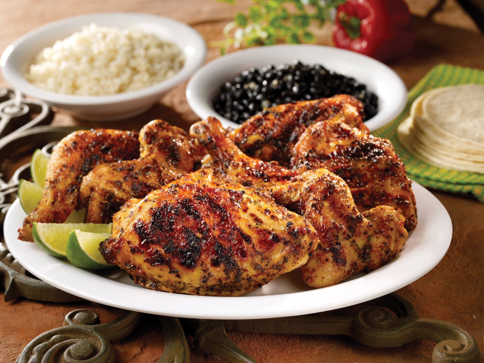 2K Quad HD PC desktop wallpaper: close-up of grilled chicken quarters on a white plate with lime wedges, rice and black beans in background — food, meat.