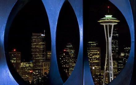 Nighttime view of Seattle’s skyline featuring the illuminated Space Needle framed by man-made architectural elements, captured as an HD PC desktop wallpaper.