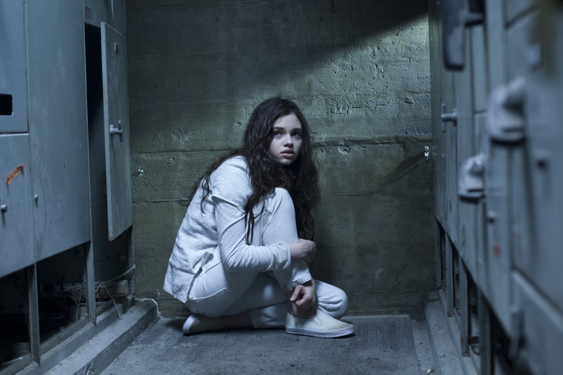 Crouching woman in a white jacket in a dim concrete locker room — scene from the movie Underworld: Awakening; 2K Quad HD PC desktop wallpaper/background.