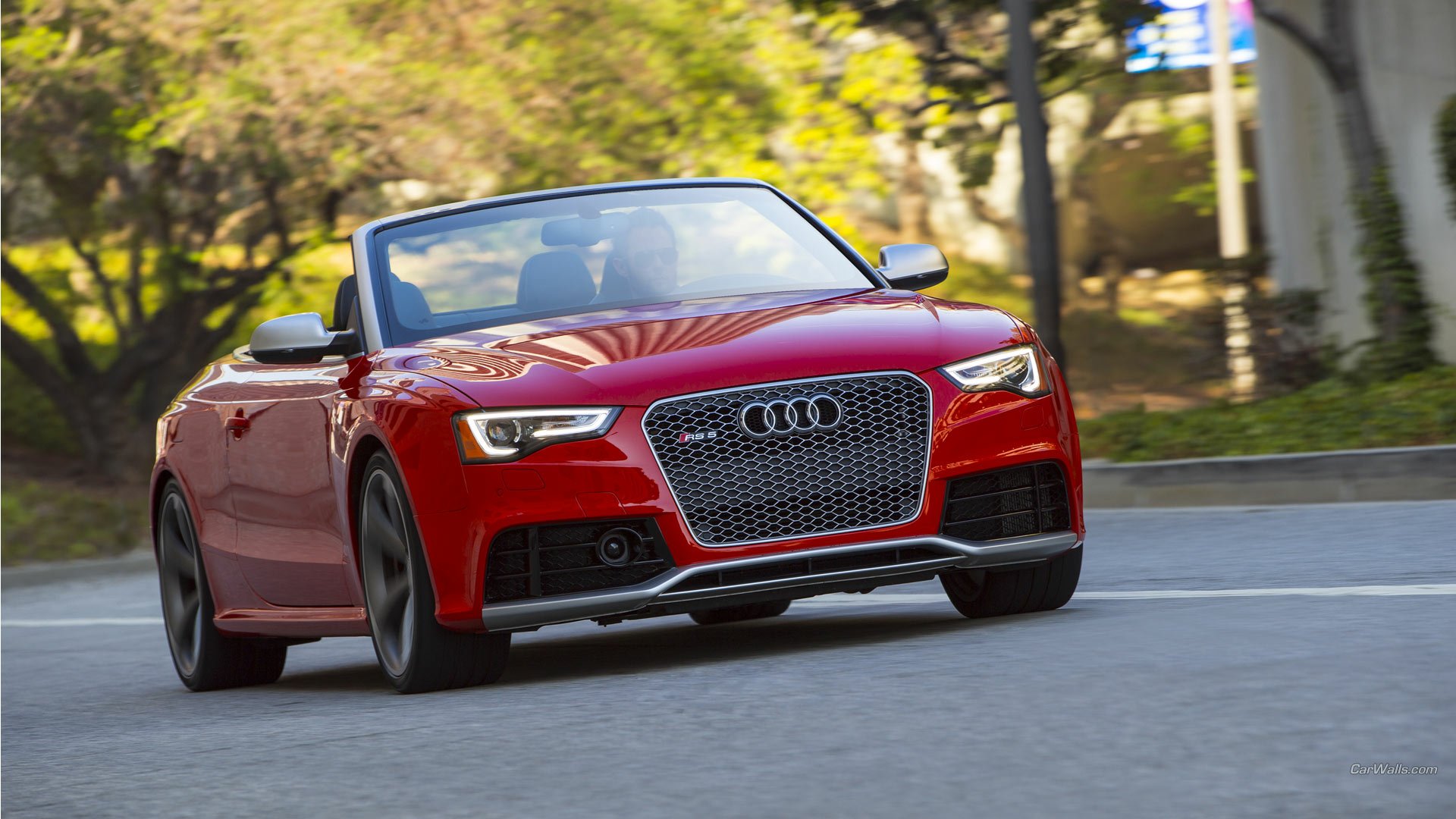 Red Audi RS5 convertible driving on a sunlit, tree-lined street — HD PC desktop wallpaper/background.