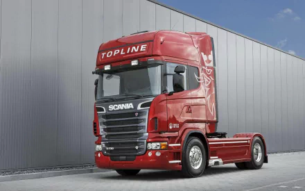 HD desktop wallpaper featuring a red Scania Topline truck parked beside a modern industrial building under clear skies.