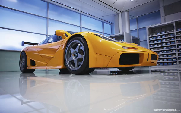A stunning McLaren F1 in vibrant orange, showcased in a sleek, modern garage setting. This HD image serves as an engaging desktop wallpaper, highlighting automotive excellence.