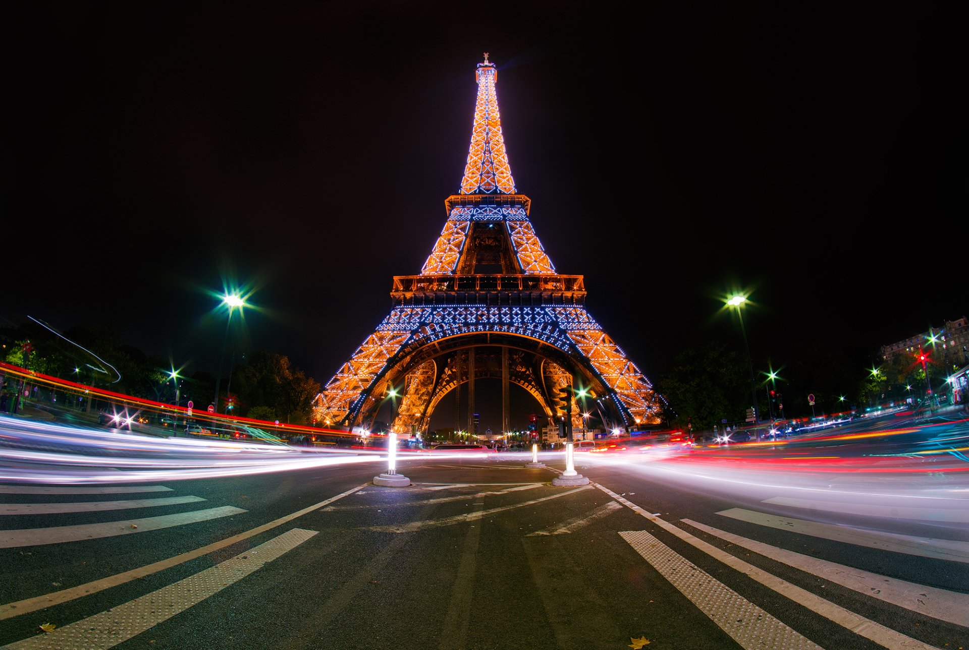 A stunning HD desktop wallpaper showcasing the Eiffel Tower illuminated at night, surrounded by vibrant city lights in Paris. A striking man-made marvel that captures the essence of the city.