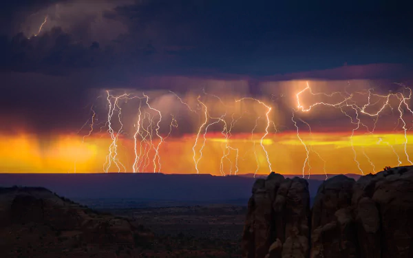 HD desktop wallpaper capturing a dramatic lightning storm striking over a desert landscape at dusk, with vivid orange and purple skies in the background.