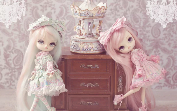A charming HD wallpaper featuring two man-made dolls in pastel outfits, posing beside an ornate music box on a vintage dresser against a delicate patterned background.