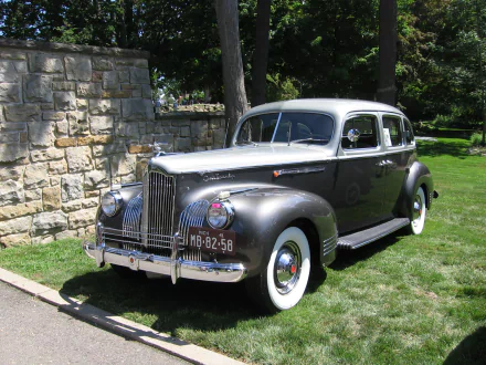 HD PC desktop wallpaper background: polished gray Packard 180 vehicle — vintage sedan with chrome grille and whitewall tires parked on a lawn beside a stone wall.