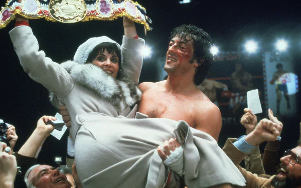HD desktop wallpaper from the movie Rocky. The image features a triumphant scene where a victorious boxer lifts a woman while surrounded by a cheering crowd.