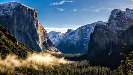 HD wallpaper of Yosemite National Park in winter showing snow-capped cliffs and a misty valley.