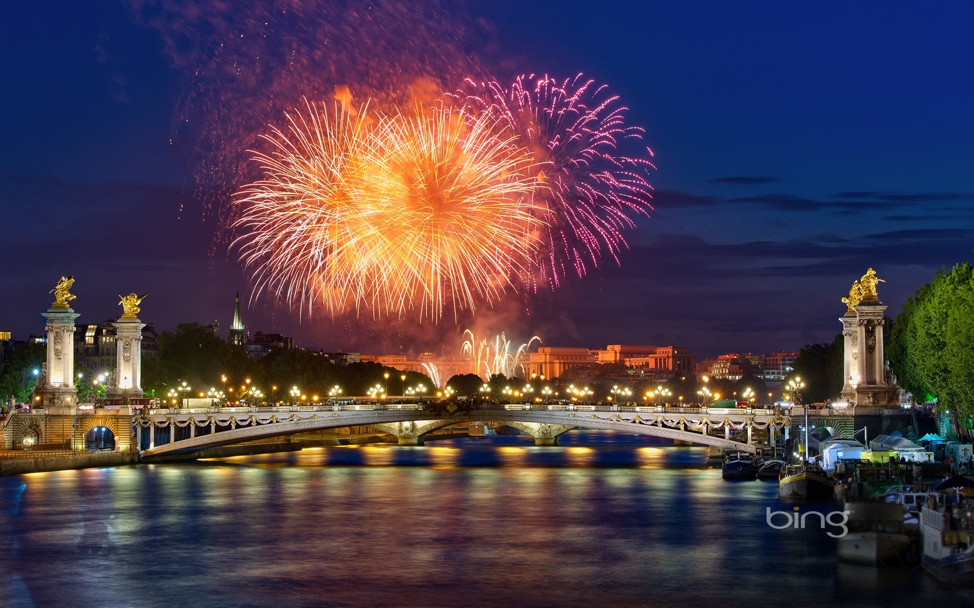 HD desktop wallpaper featuring vibrant fireworks lighting up the night sky over a historic bridge and river, captured in stunning photography.