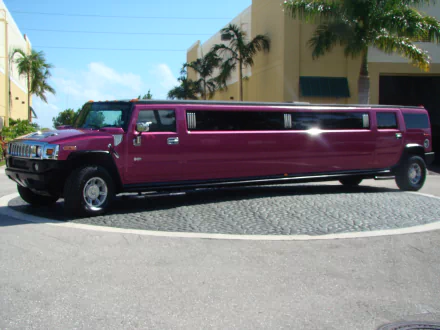 A sleek, maroon Hummer limousine parked on a sunlit street, captured in HD quality for a vibrant desktop wallpaper and background.