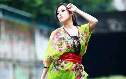 HD desktop wallpaper featuring a Korean woman in a vibrant floral dress with a red belt, posing gracefully outdoors.