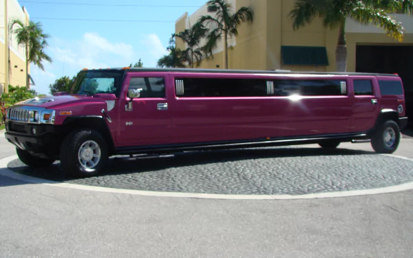 A sleek, maroon Hummer limousine parked on a sunlit street, captured in HD quality for a vibrant desktop wallpaper and background.