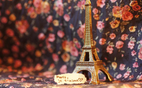 2K Quad HD PC desktop wallpaper: a man-made miniature Eiffel Tower replica on a floral fabric background with a Paris, je t'aime note in the foreground.