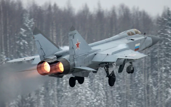 Military HD PC desktop wallpaper: Mikoyan MiG-31 interceptor with afterburners blazing, climbing over a snow‑covered forest backdrop.