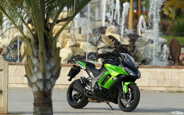 HD PC desktop wallpaper featuring a green Kawasaki Z1000SX motorcycle parked near a palm tree with a decorative fountain in the background.