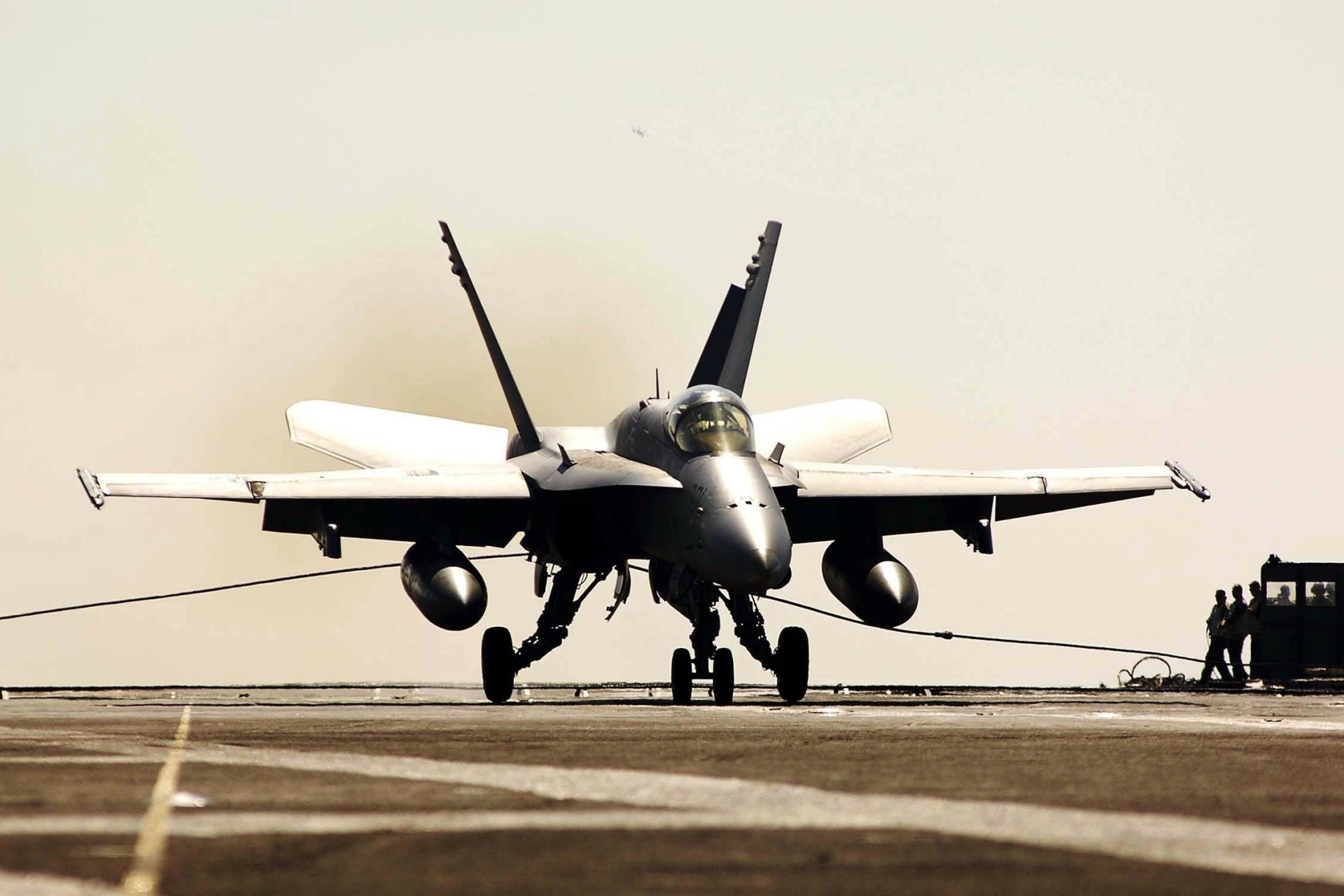 HD desktop wallpaper of a McDonnell Douglas F/A-18 Hornet military jet on a runway, captured head-on with a neutral, light background.